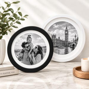 Puede incluir: Dos marcos de fotos circulares, uno negro y otro blanco, cada uno con una fotografía en blanco y negro. El marco negro muestra a una familia de tres personas, mientras que el marco blanco muestra la torre del reloj Big Ben y el Parlamento.