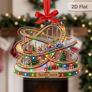 May include: A flat, 2D Christmas ornament featuring a golden roller coaster track with small cars carrying Santa Claus and a reindeer. The base is decorated with Christmas trees, wrapped gifts, and colorful string lights, with the text NAME 202X.