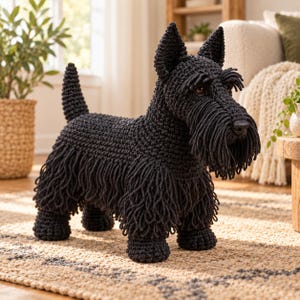 May include: A handcrafted black crochet Scottish Terrier dog figurine featuring a textured yarn body, pointed ears, a short upright tail, and long fringe detailing around the face and legs, with dark brown eyes and a black nose.