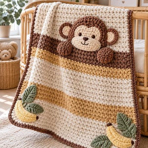 May include: A crochet baby blanket featuring horizontal stripes in cream, tan, and brown. The blanket includes a large, three-dimensional brown monkey face appliqué at the top and two yellow banana appliqués with green leaves at the bottom corners.