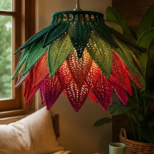 May include: A hanging pendant lamp shade crafted from crocheted fabric shaped like layered leaves. The top section features dark and light green leaves, transitioning into vibrant red and deep magenta leaves at the bottom, emitting a warm glow.