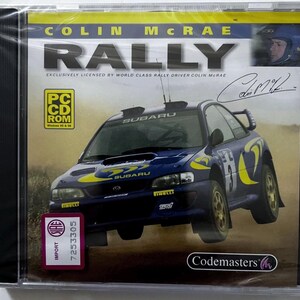 May include: A Colin McRae Rally PC CD-ROM game case featuring a blue Subaru rally car on the cover. The artwork includes the text Colin McRae Rally, a signature, a small portrait of a driver, a PC CD-ROM logo, and a pink SIAE import sticker.