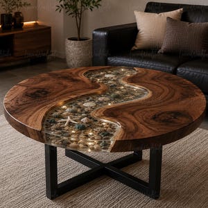 May include: A round coffee table featuring a natural wood slab with a live edge and a central river section filled with clear resin, embedded with various seashells, pebbles, and small integrated LED lights, supported by a black metal X-frame base.