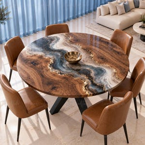 May include: A round dining table featuring a natural wood grain surface with a central river-like inlay of blue, white, and black resin accented with gold leaf, supported by a black metal base, surrounded by five tan leather upholstered chairs.