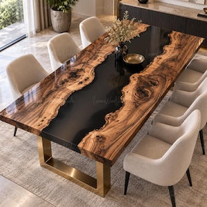 Puede incluir: Una mesa de comedor rectangular con dos tablones de madera de borde natural con vetas y nudos prominentes, separados por una incrustación central de resina negra. La mesa se apoya sobre una base de metal dorado cepillado en forma de U.