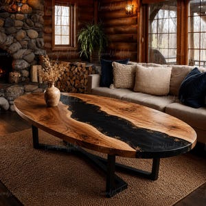May include: An oval coffee table featuring a natural wood slab with a prominent black resin river inlay running through the center. The table is supported by a black metal base and displays a smooth, polished finish on the wood grain surface.