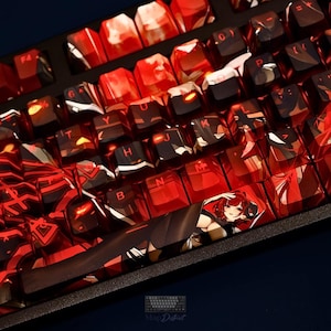May include: A mechanical keyboard featuring custom keycaps with a vibrant red and black abstract pattern. The spacebar displays a detailed illustration of an anime-style character with red hair. Each keycap has clear, legible lettering in a bold font.
