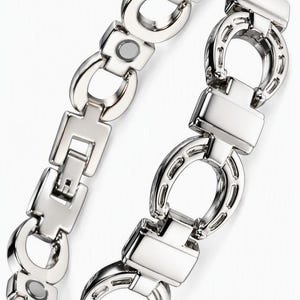 May include: A silver-toned metal link bracelet featuring alternating horseshoe-shaped links and rectangular connectors. The bracelet includes integrated circular magnetic elements embedded within the links and a secure fold-over clasp mechanism.