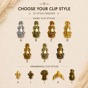 May include: A collection of 12 metal clips labeled A through L, featuring hand-shaped designs with cuffs and ornamental shapes like fleur-de-lis, flowers, and mermaid tails in silver, gold, and black finishes, with some featuring small white pearls.