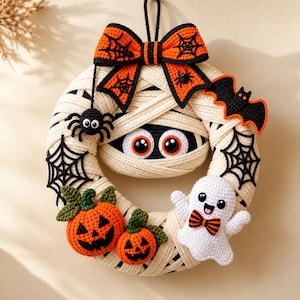 Könnte beinhalten: Ein runder Häkel-Halloween-Kranz, der mit cremefarbenem Garn umwickelt ist, um wie eine Mumie auszusehen. Er ist mit einer großen orangefarbenen Schleife mit Spinnennetzen, einer schwarzen Fledermaus, einer Spinne, zwei Kürbissen und einem Geist verziert.