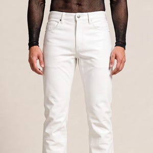 May include: A pair of solid white denim jeans featuring a classic five-pocket design, a button fly closure, and a straight-leg cut. The jeans are constructed with visible stitching along the seams and pockets, providing a clean and structured appearance.