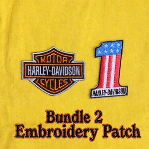 May include: Two embroidered patches on a yellow fabric background. One patch is a black and orange Harley-Davidson shield logo. The other is a number one patch with a blue and white star field and red and white stripes, featuring the text Harley-Davidson.