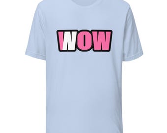 May include: A light blue short-sleeve t-shirt featuring the word WOW printed in a bold, block-style font across the chest. The letters are colored in a vibrant pink with a thick black outline, creating a graphic design on the front.