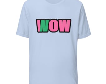 May include: A light blue short-sleeve t-shirt featuring the word WOW printed in the center. The letter W is green, while the letters O and W are pink. Each letter is outlined in a thick black border, creating a bold graphic design on the front.