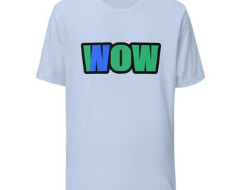 May include: A light blue short-sleeve t-shirt featuring the word WOW printed in a bold, blocky font across the chest. The letters are outlined in black, with the W colored in blue and the O and W colored in a vibrant green shade.