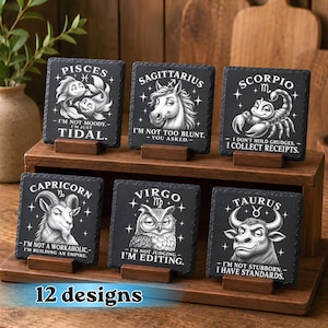 May include: Six square black slate coasters featuring white zodiac illustrations and humorous text. The designs include Pisces, Sagittarius, Scorpio, Capricorn, Virgo, and Taurus, each with a unique animal graphic and witty caption printed in white.