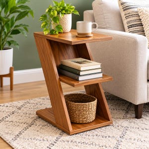 Op de afbeelding: Een Z-vormige bijzettafel van bruin hout met een gladde afwerking. De tafel heeft een bovenblad, een middelste plank met drie gestapelde boeken en een onderste basis met een ronde gevlochten mand. Het ontwerp is hoekig en open.