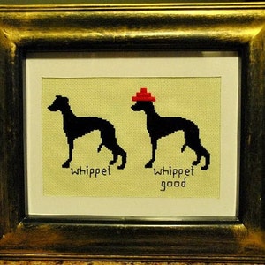Puede incluir: Obra de arte en punto de cruz enmarcada que muestra dos siluetas negras de perros whippet. Uno de los perros lleva un sombrero rojo. El texto debajo dice "whippet" y "whippet good". Fondo amarillo claro, marco dorado.