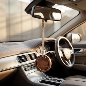 May include: A circular dark brown wooden car air freshener hanging from the rearview mirror by a thick, light-colored braided rope. The wooden piece features a smooth, flat circular center framed by a slightly raised outer wooden ring.