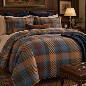 May include: A bedding set featuring a plaid pattern in shades of blue, brown, and tan. The set includes a duvet cover, two matching rectangular pillows, two solid white pillows, two dark blue accent pillows, and a solid brown lumbar pillow.