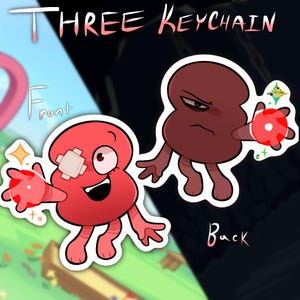 May include: Two character-shaped keychains labeled THREE KEYCHAIN with FRONT and BACK views. The front shows a red figure with a bandage on its head and a red orb. The back shows a dark brown figure with a stern expression and a red orb.