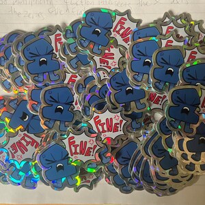 May include: A collection of holographic stickers featuring a blue cartoon character with a frustrated expression. Each sticker has a jagged, comic-style speech bubble background with the red text "Fine!" and small red angry symbols.