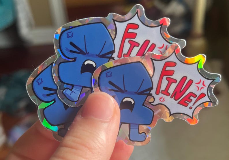 May include: A holographic sticker featuring a blue, anthropomorphic character with an angry expression and a speech bubble containing the red text "FINE!". The character has a furrowed brow, clenched teeth, and small limbs, with a star-like symbol.