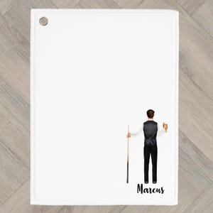 May include: White rectangular towel with a grommet in the upper left corner. A graphic of a person in a vest and black trousers holding a pool cue and a glass of beer is on the bottom right. The name "Marcus" is written below.
