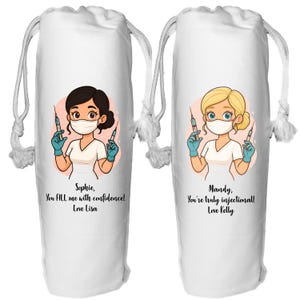 May include: Two white drawstring bags with cartoon illustrations of nurses holding syringes. One features a brunette nurse with the text "Sophie, You FILL me with confidence! Love Lisa." The other shows a blonde nurse with the text "Mandy, You're truly injectional! Love Kelly."