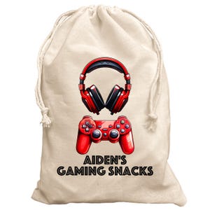 May include: A white drawstring bag with a red video game controller and red headphones printed on it. The text "Aiden's Gaming Snacks" is printed below the controller and headphones.