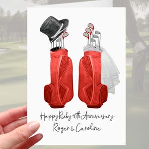 Op de afbeelding: Een wenskaart met twee rode golftassen, elk gevuld met golfclubs. Eén tas heeft een zwarte hoge hoed, de andere een tiara en sluier. De tekst luidt "Happy Ruby 40th Anniversary Roger & Caroline."