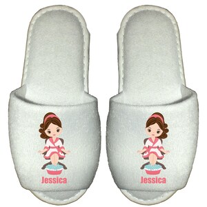 May include: Pair of white spa slippers with a cartoon illustration of a woman getting a foot massage. The slippers have the name "Jessica" printed on them.
