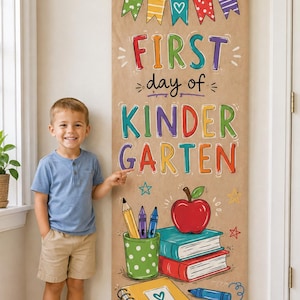 May include: A vertical tan fabric banner hanging from a wooden rod, featuring colourful illustrations of school supplies, a red apple, and the text FIRST day of KINDERGARTEN in multi-coloured letters, decorated with bunting and stars.
