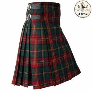 May include: A pleated kilt featuring a dark green, red, and yellow tartan plaid pattern. The garment includes two black leather straps with silver-toned metal buckles on the side for adjustment. The fabric has a structured, folded design.