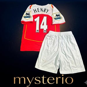 May include: A red and white football shirt featuring the name HENRY and the number 14 on the back, paired with plain white football shorts. The shirt includes two Barclays Premier League patches on the sleeves and yellow trim accents on the front.