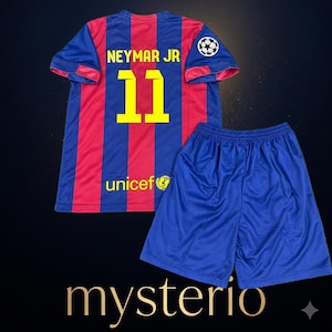 以下が含まれることがあります： 黄色でNEYMAR JRと11の文字が入った青と赤のストライプのサッカーシャツ。袖にはユニセフのロゴとチャンピオンズリーグのワッペンが付いており、無地の青いサッカーショーツとセットになっています。下にmysterioという文字が印刷されています。