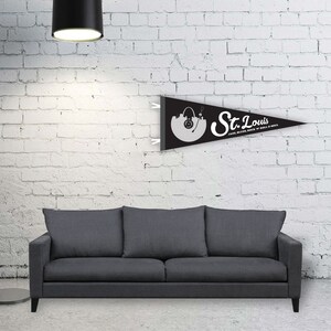 May include: Black and white pennant flag with the text "St. Louis" and the words "Jazz, Blues, Rock 'n' Roll, Soul". The flag features a stylized image of the St. Louis skyline with a record player.