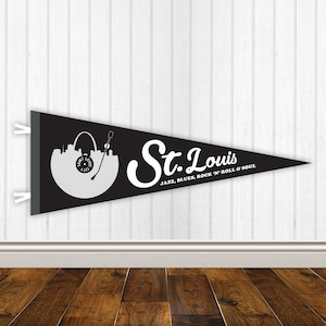 May include: Black pennant flag with a white silhouette of the St. Louis Arch and a record player. The text "St. Louis" is written in a white cursive font with the words "JAZZ, BLUES, ROCK 'N' ROLL & SOUL" below.