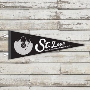 May include: Black and white pennant flag with a record design featuring the St. Louis skyline and the text "St. Louis" with the tagline "Jazz, Blues, Rock 'n' Roll & Soul".