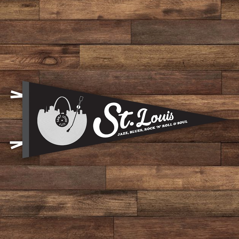 May include: Black pennant flag with a white silhouette of the St. Louis skyline and a record player. The text "St. Louis" is written in a white cursive font with the words "JAZZ, BLUES, ROCK 'N' ROLL & SOUL" below.