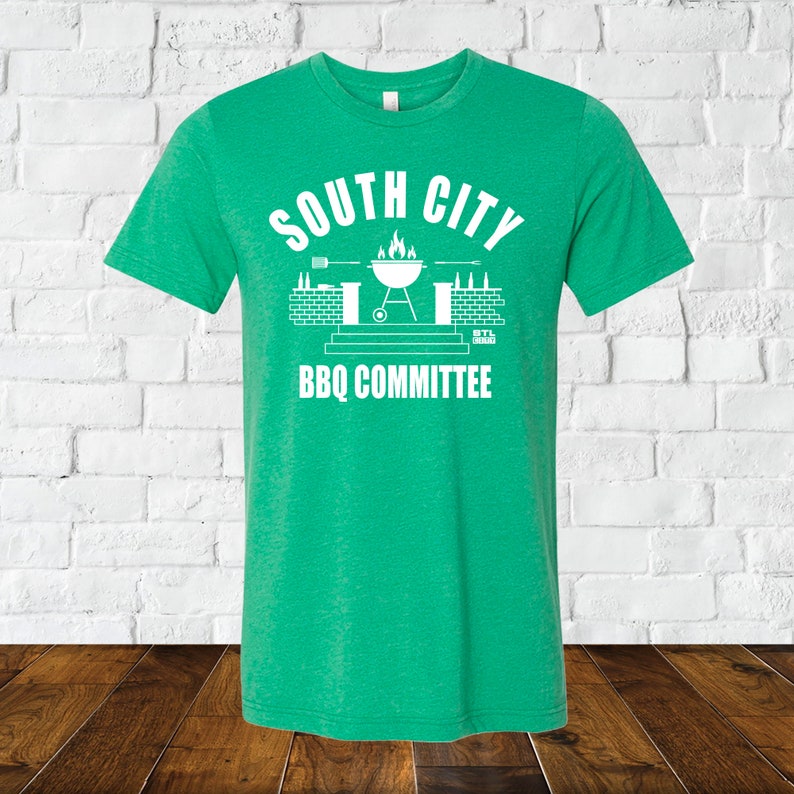 May include: Green t-shirt with a white graphic of a grill, brick wall, and the text "South City BBQ Committee".
