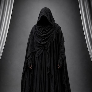 May include: A full-length black hooded cloak featuring a layered, distressed fabric design with frayed edges. The garment includes a deep cowl hood that obscures the face, long sleeves with fingerless glove details, and a flowing, pleated skirt.