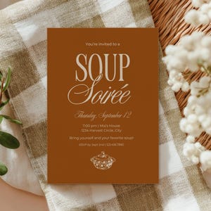 Puede incluir: Una tarjeta de invitación rectangular con fondo naranja quemado y texto en blanco que dice: You're invited to a SOUP Soirée, Thursday, September 12, 7:00 pm | Mia's House, 1234 Harvest Circle, City, Bring yourself and your favorite soup! RSVP by Sept 2nd | 123.456.7890. Un pequeño dibujo lineal blanco de una sopera con tapa está centrado en la parte inferior.