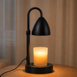 Puede incluir: Una lámpara calentadora de velas en color negro mate con cuello curvo y pantalla en forma de cúpula. La lámpara cuenta con una base circular que sostiene un frasco de vela de vidrio esmerilado, que emite una luz cálida, con cable negro.