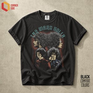 Może przedstawiać: Czarny t-shirt z krótkim rękawem z grafiką zespołu The Mars Volta, przedstawiającą cztery stylizowane portrety osób z kręconymi włosami. Napis "THE MARS VOLTA" jest nadrukowany jasnoniebieską czcionką nad głównym motywem graficznym.