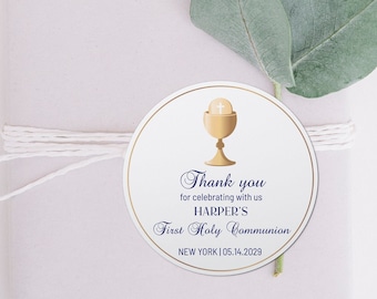 May include: A white round favor tag with a gold chalice and host design. The text reads "Thank you for celebrating with us HARPER'S First Holy Communion NEW YORK | 05.14.2029"