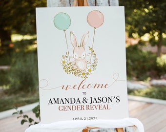 May include: A wooden easel displays a sign for Amanda & Jason's Gender Reveal. The sign features a bunny holding balloons, with the words "welcome to" and the event details. The date is April 21, 2025.