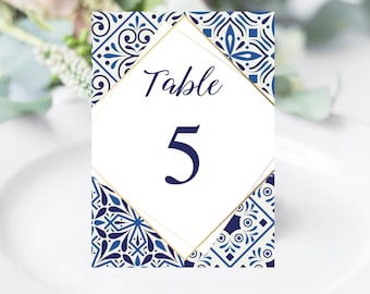 May include: Blue and white table number card with gold trim. The card has a diamond shape with the text "Table 5" in the center.