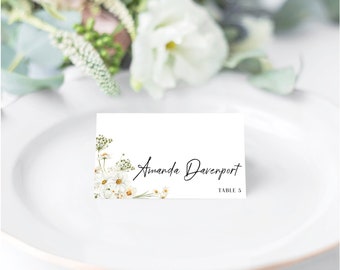 May include: White place card with a floral design featuring white daisies and green leaves. The text "Amanda Davenport" and "Table 5" is printed in black.