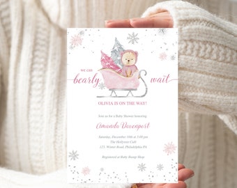 Könnte beinhalten: Eine rosa und weiße Babyparty-Einladung mit einem Comic-Bären in einem rosa Schlitten. Die Einladung lautet "We can barely wait" und "Olivia is on the way!" Die Einladung enthält auch das Datum, die Uhrzeit und den Ort der Party.